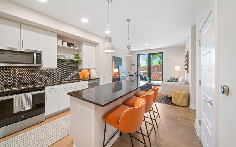 a kitchen with white cabinets, an island and chairs